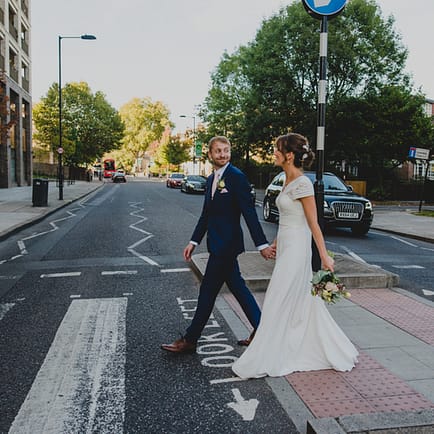 a bride and groom crossing the road in London